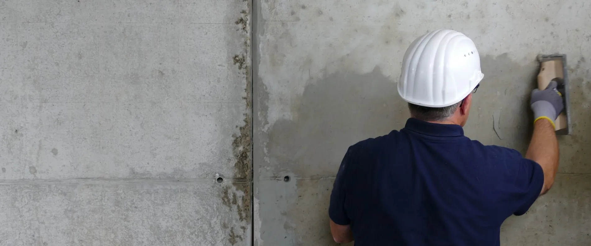 Ein Spachtel wird an eine Betonwand appliziert.