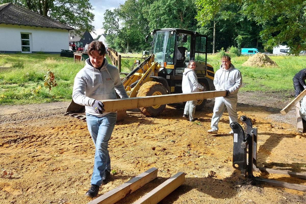 Die Auszubildenden der MC tragen die Holzbalken für den Bau eines Unterstands.